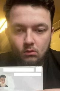 Руската бойна група Dylan Earl holds up his passport, showing his photo and personal details.