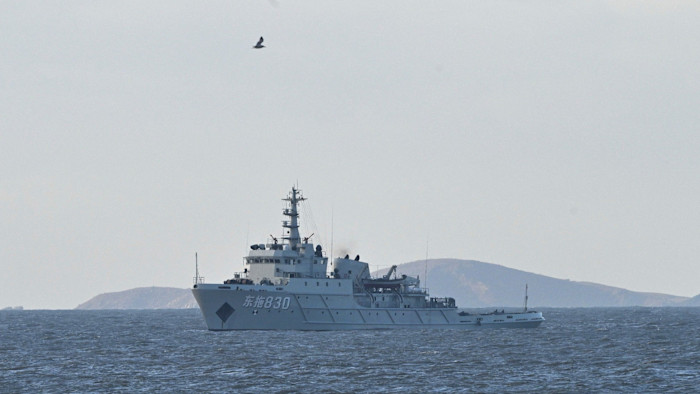 A Chinese military ship with hull number 830 patrols the sea near Pingtan island, with distant hills in the background