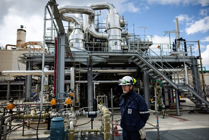 A worker in protective gear stands by industrial piping and equipment at the Kem One petrochemical plant’s electrolyzer installation.