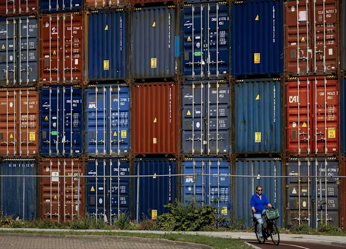 A person rides a bicycle past stacked shipping containers at the Waalhaven in the Port of Rotterdam.