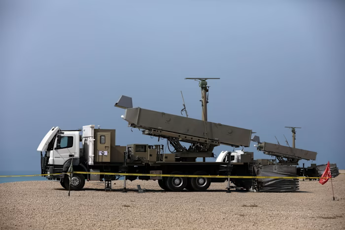 An Iranian missile system mounted on a truck is positioned on a sandy shore during military exercises.